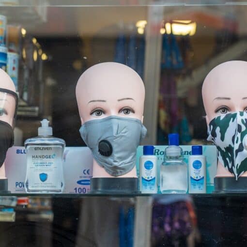 A picture of facemasks on tailor dummy heads in a pharmacy window showing the new normal