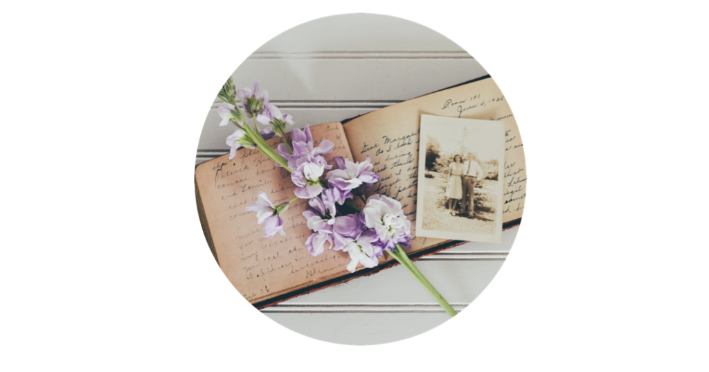 Old diary and photo album with a lilac flower laid over at an angle.