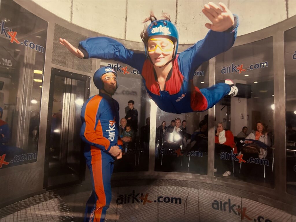 Photo of Nina wearing the helmet and body suit to do the fly in. Arm stretched out and free flying!